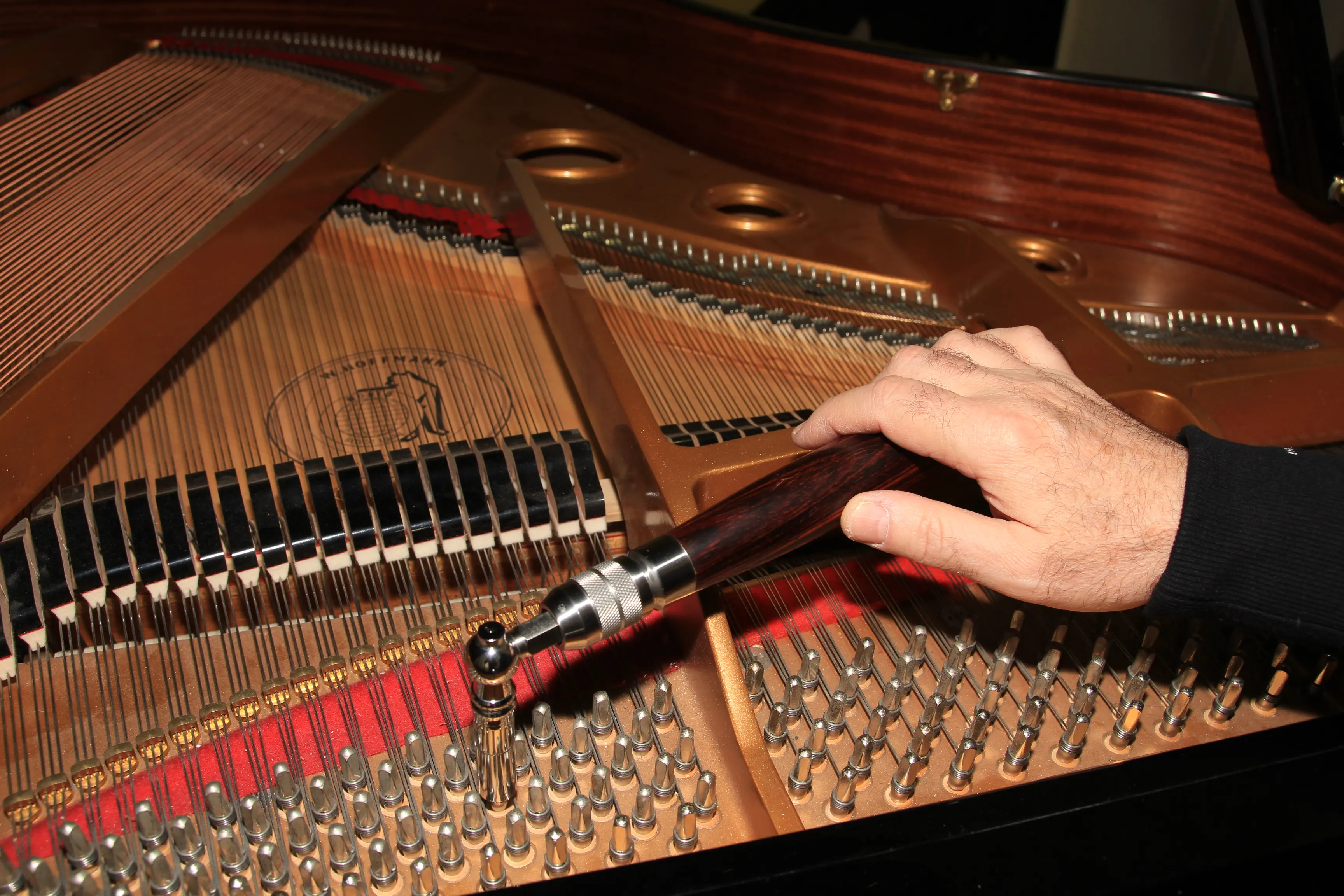 Hand mit Stimmhammer auf den Stimmwirbeln eines W. Hoffmann Flügels